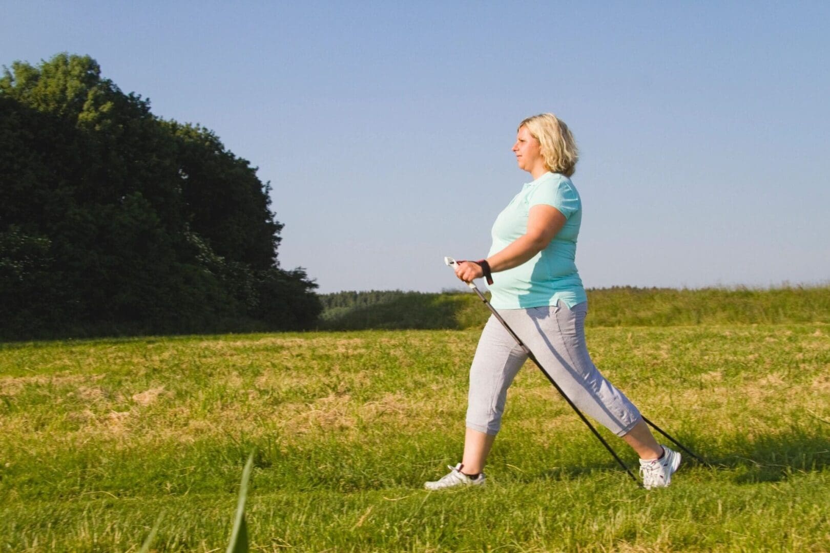 Woman Nordic walking outdoors in a grassy field